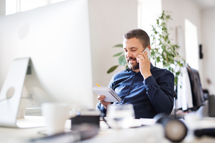 male talking on the phone holding a notepad