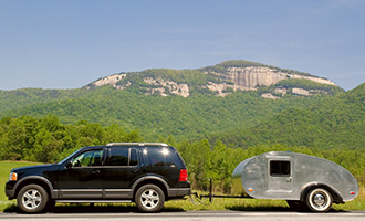 An black SUV pulling a tsilver ravel trailer